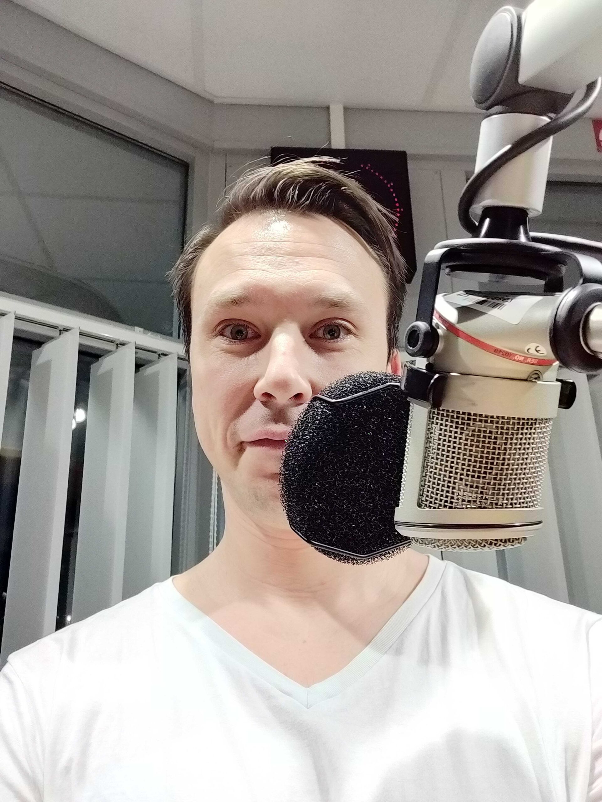Jonas i halvfigur, leendes bakom en radiomikrofon i en studio.